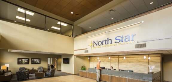 A man stands at the North Star Mutual Insurance reception desk in a bright, modern, and spacious lobby.